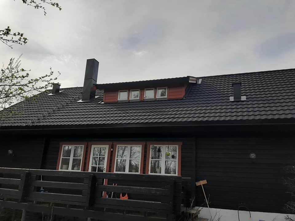 The finished black roof on the timber house, with a chimney and roof ladder