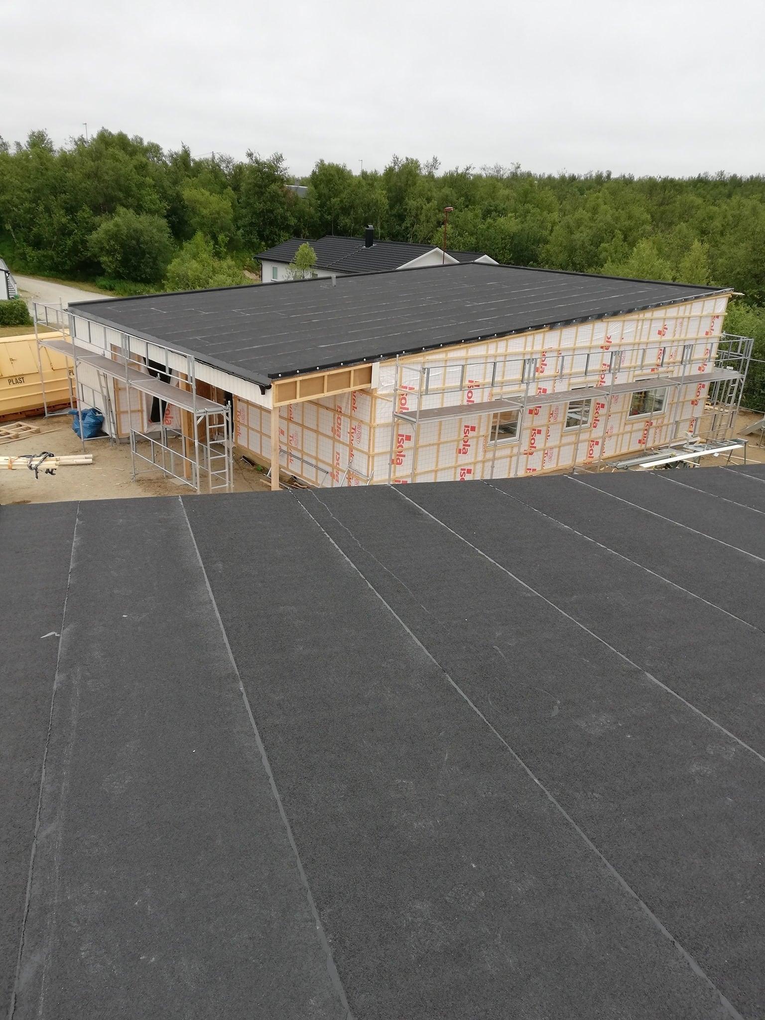 A flat roof with a new dark membrane on a building site