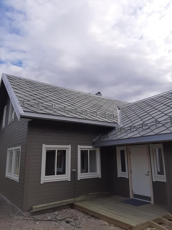 A grey house with a new dark roof over the entrance