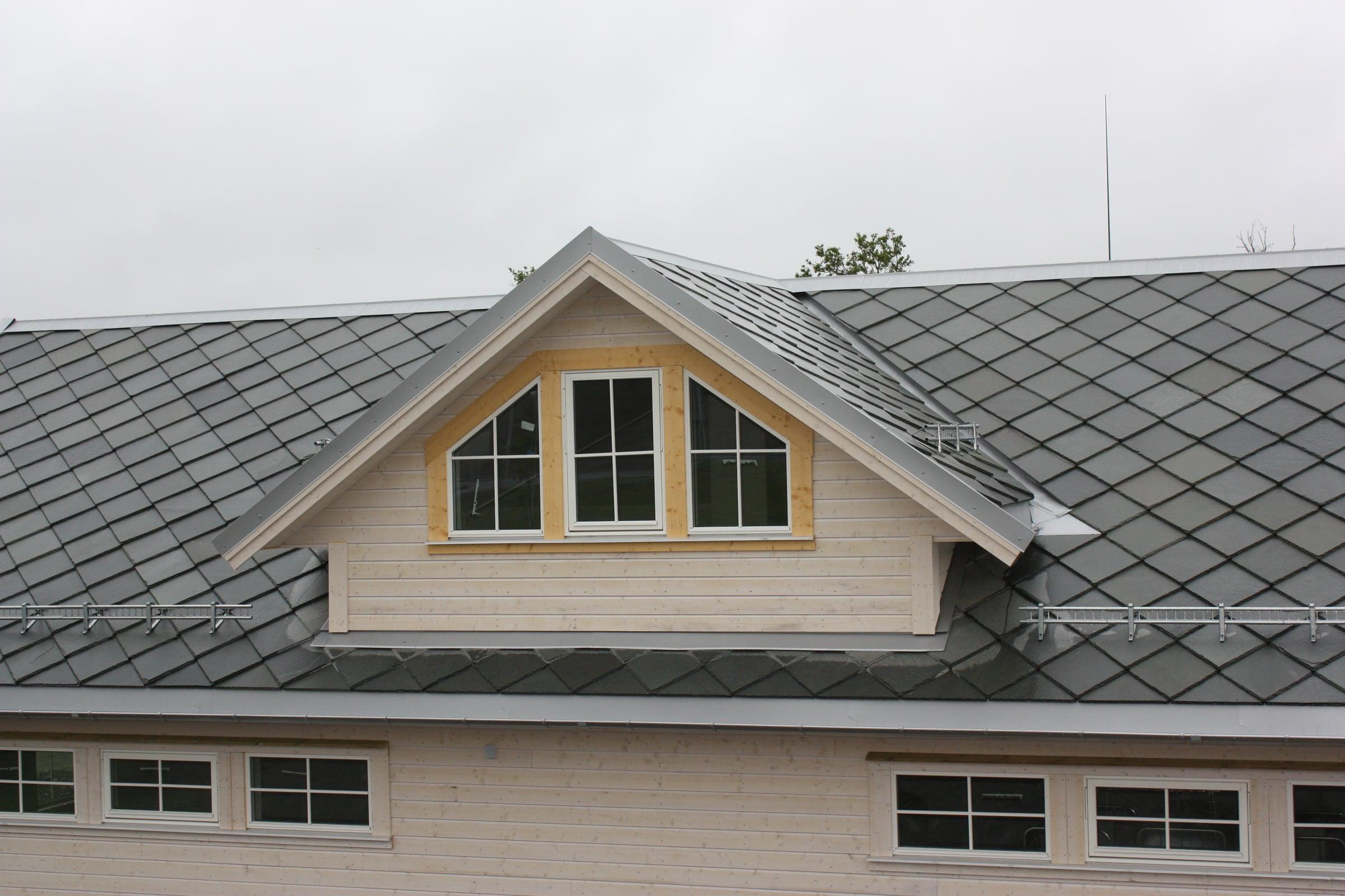 A grey slate roof laid in a diamond pattern, with a dormer and white-framed windows